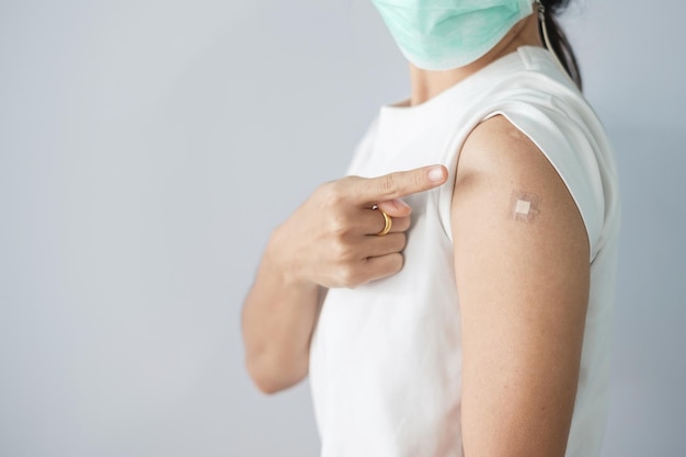 코비드 19 백신을 받은 후 붕대를 보여주는 여성. 예방 접종, 무리 면역, 부작용, 부스터, 백신 여권 및 코로나 바이러스 전염병