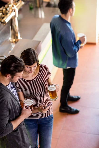 Woman showing cellphone to boyfriend while having beer