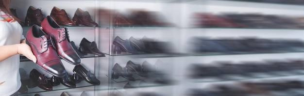 Woman showing elegant leather male shoe in the store