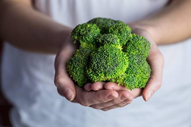 Женщина показывает свежие зеленые brocolli