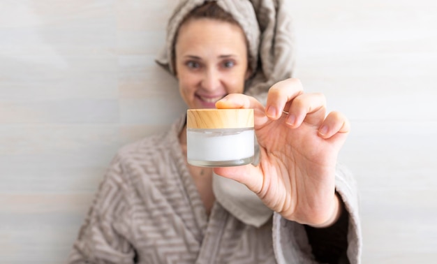 Photo woman showing in front a cream to hydrate after bath or shower