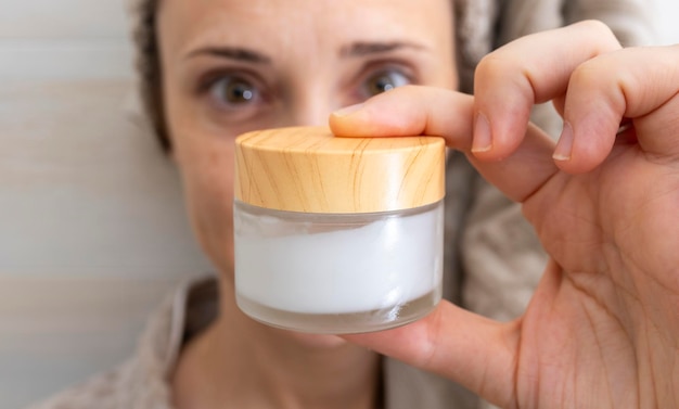 Photo woman showing in front a cream to hydrate after bath or shower