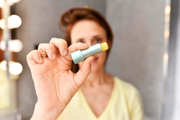 Photo woman showing in front a yellow lipstick care i have hydration of the lips