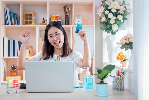 Woman showing of happiness after shopping online with the life style New Normal for self quarantine during the outbreak Corona virus Disease (COVID-19)