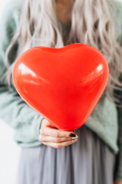 Woman showing a heart red balloon