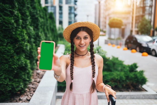 Woman showing modern smartphone with green screen for replacement