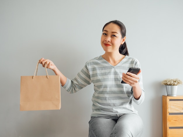 Woman showing off empty paper bag of product she purchased online.