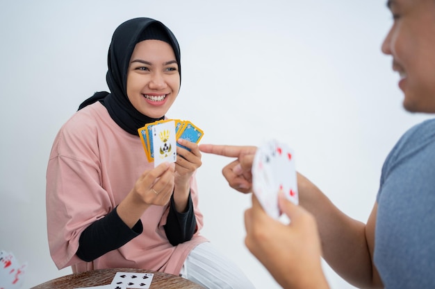 Woman showing one card while playing cards with male friends