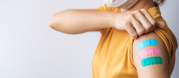 Woman showing plaster after receiving covid 19 vaccine. Vaccination, herd immunity, side effect, booster dose, vaccine passport and Coronavirus pandemic