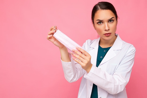 Donna che mostra la maschera di protezione isolata sul rosa