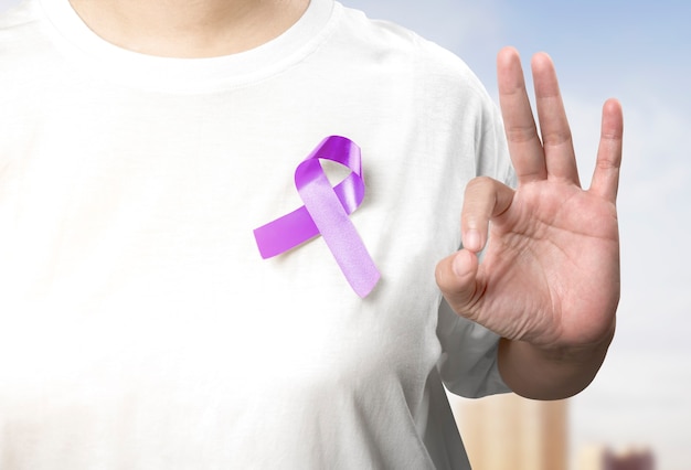 Woman showing purple ribbon on her chest. World Cancer Day concept