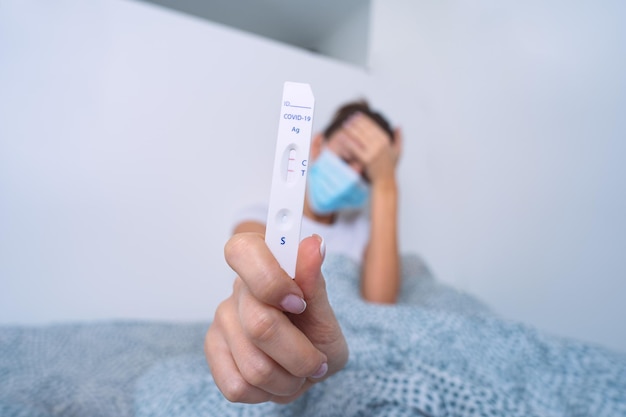 woman showing rapid covid antigen test or express covid test with positive result