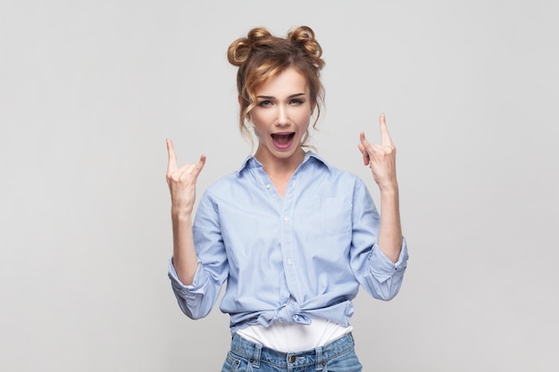 Woman showing rock and roll gesture heavy metal sign enjoying favorite music on party has fun