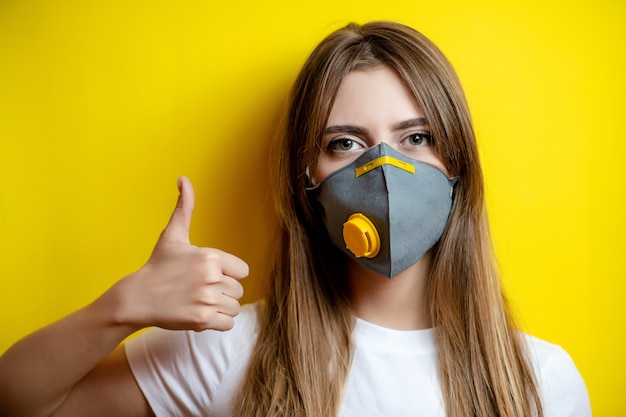 Photo woman showing thumbs up wearing respirator