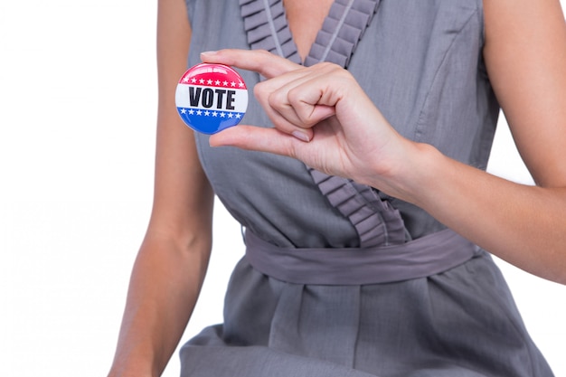 Foto una donna che mostra il distintivo di voto su fondo bianco