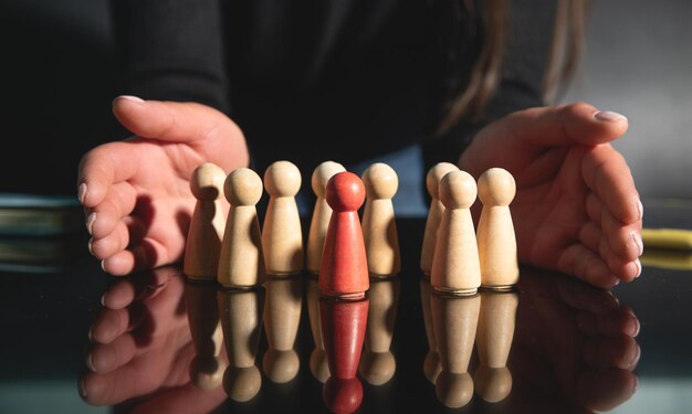 Woman showing wooden human figures Recruitment Leadership