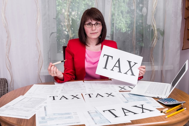 Woman showing word 'tax' on sheet of paper