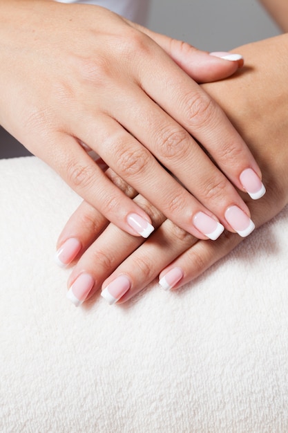 The woman shows a beautiful French manicure putting hand on one another