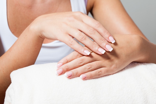 The woman shows a beautiful French manicure putting hand on one another