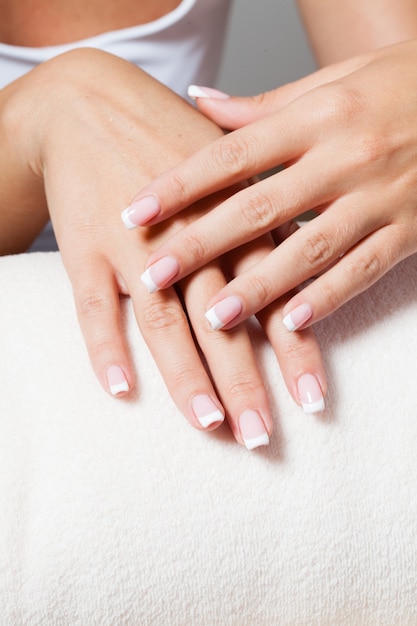 The woman shows a beautiful French manicure putting hand on one another