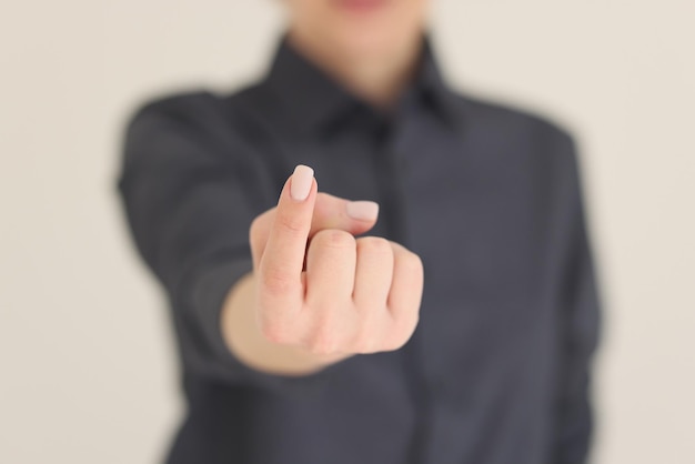 Woman shows beckoning sign in camera on beige background