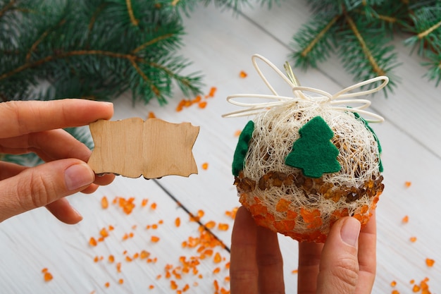 Woman shows craft christmas ball with wooden lable