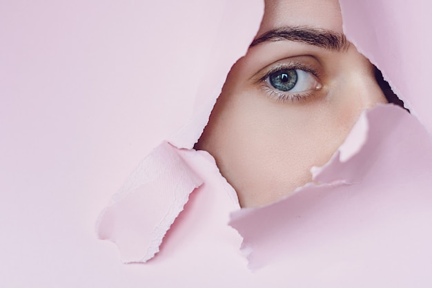 Woman shows eye through broken wall