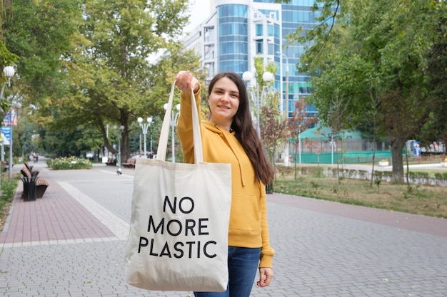 A woman shows a fabric reusable bag with the text no more plastic.