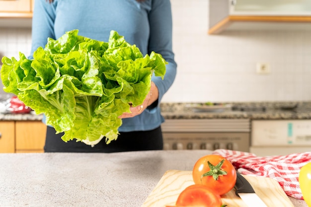 여자는 집 부엌에서 샐러드나 건강한 식사를 만들기 위해 신선한 녹색 상추를 보여준다