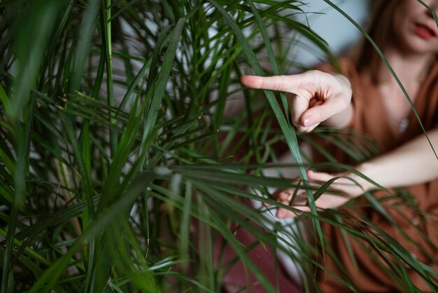 写真 緑の葉の背景に指を横に示す女性