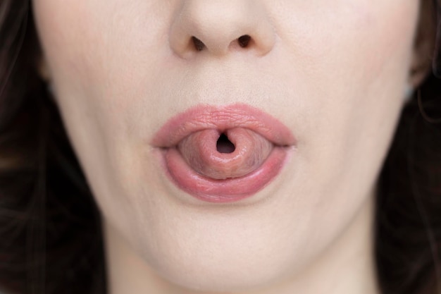 チューブのクローズアップに折りたたまれた舌を示す女性
