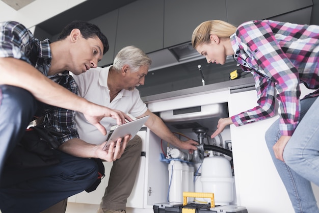 Photo a woman shows plumbers a broken kitchen sink