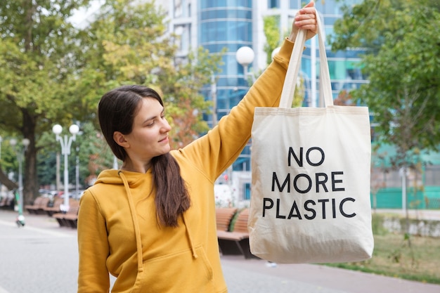 女性はもはやプラスチックではないテキストで再利用可能なバッグを示しています