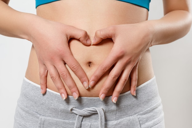 Woman shows two hands gesture heart on his stomach. on white. Concept of women's health, early pregnancy