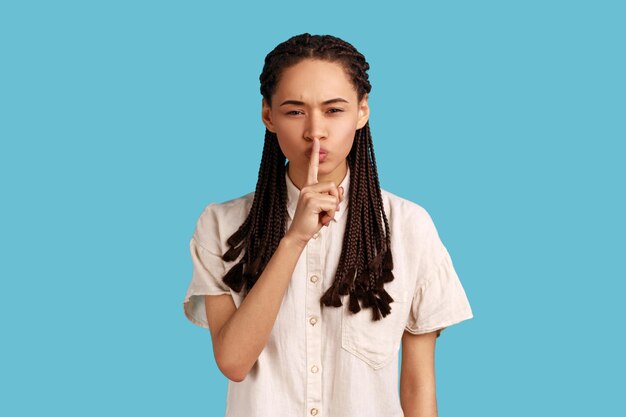 Woman shushes with angry face makes taboo gesture tells to be quiet demands not to spread rumors