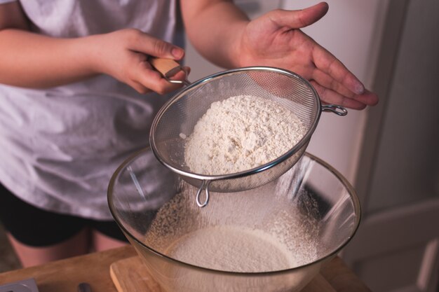 ボウルに小麦粉をふるいにかける女性