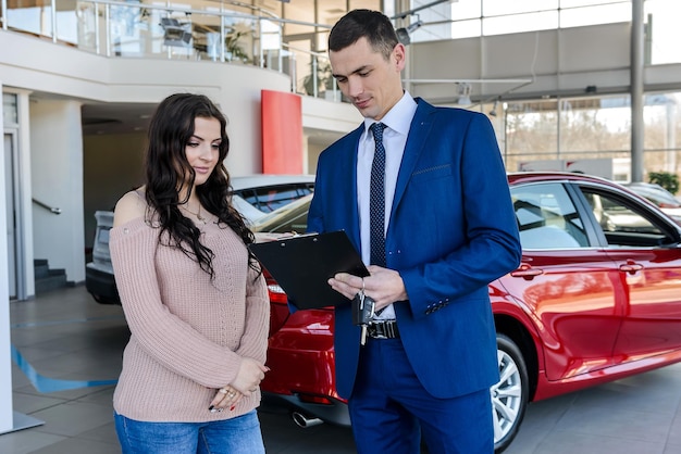 Woman signing contract with dealer in showroom