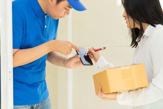 Woman signing on smart phone while receiving cardboard boxes