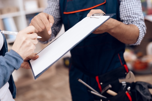 a woman signs an act of work done by a repairman.