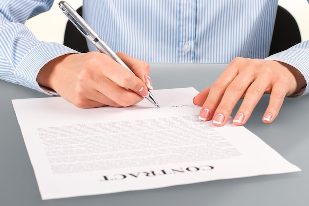 Woman signs contract at desk. Female signing contract at desk. Employer at the working desk. Recruiter at her workplace.