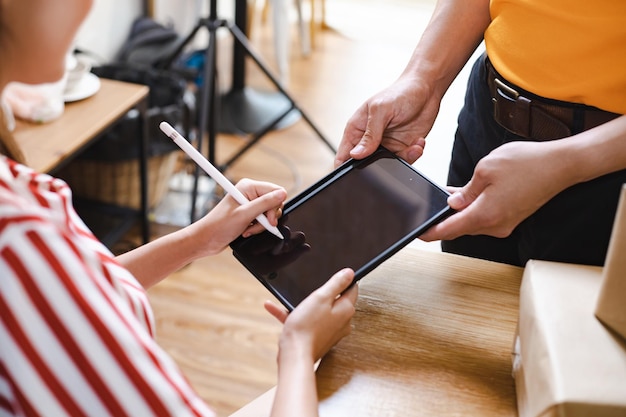 写真 郵便配達員から小包を受け取るためにタブレットに署名する女性