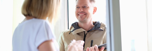 Woman signs on a tablet for parcel from courier at home