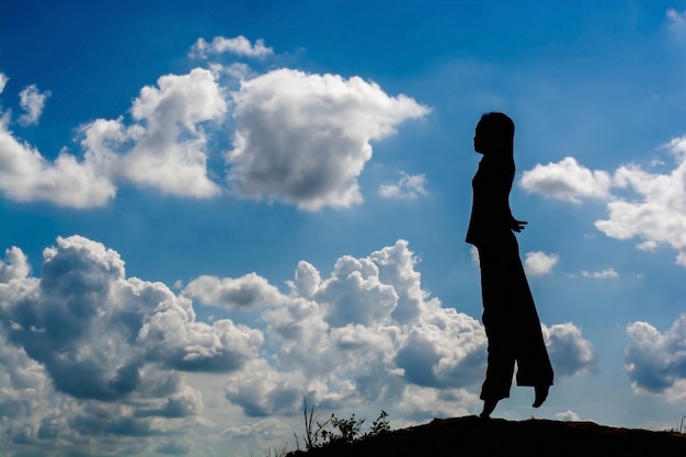 Woman silhouette standing raise hand on sunset