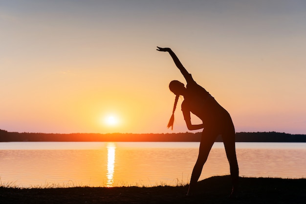 湖で夕暮れ時の女性のシルエット