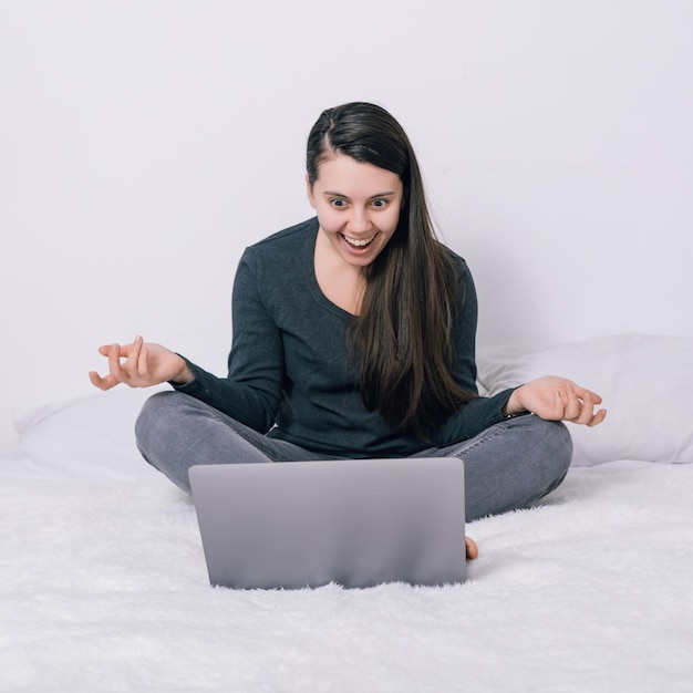 여자는 침대에 앉아서 노트북을 사용한다