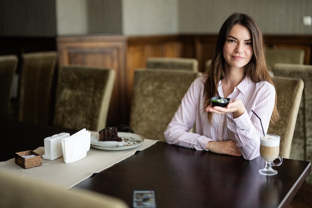 woman sit in coffee shop cafe restaurant indoors and eat chocolate brownie dessert cake show plate