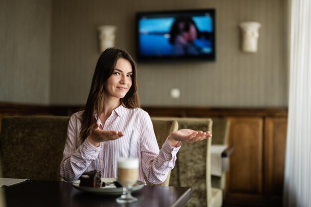 woman sit in coffee shop cafe restaurant indoors points her hands to the side