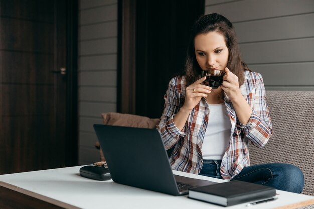 Woman sit down on the sofa at home and drinking tea