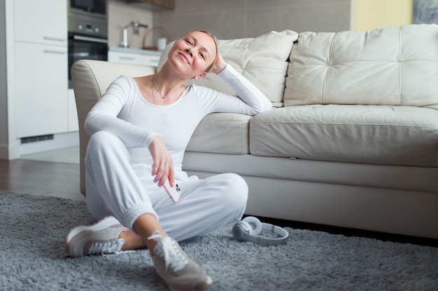 woman sit on floor at home holding smartphone smiling face