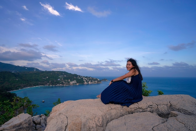 女性は海の景色の視点、タオ島のジョンスワンの視点、タイのスラタニの観光地の場所で岩の上に座ってリラックスします